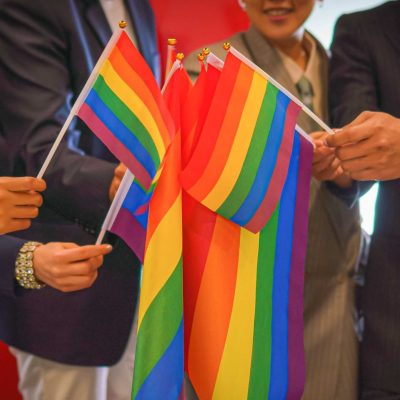 diverse group of lgbtq people with rainbow flag on hand team up diverse group of business people (man, woman, gay, transgender, lesbian, asian, caucasian, african american, lgbtq) with rainbow flag on hand combine together as teamwork in office, selective focused